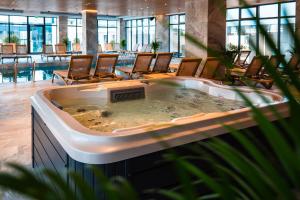 a large hot tub in a hotel lobby with chairs at Chocolat in Odyssey Pool & Spa Resort in Mamaia Sat/Năvodari
