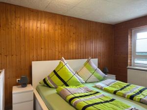 two beds in a room with wood paneled walls at Peaceful Forest Getaway in Altenfeld