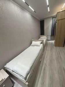 two beds in a small room with wooden floors at Shayxul Islam 5 in Bukhara