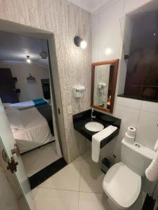 a bathroom with a sink and a toilet and a bed at Pousada Sol e Cia Tur in Caraguatatuba +234 photos