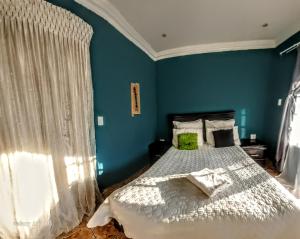 a bedroom with a large bed with blue walls at Aquamarine Guesthouse in Morula Sun