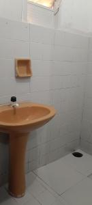a bathroom with a brown sink and white tiles at Pousada Popular in Barreiras