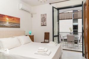 a bedroom with a white bed and a balcony at Otranto City Center - Steps from the Beach in Otranto