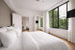 een witte slaapkamer met een groot bed en witte kussens bij The Suite Garden Hotel in Frankfurt am Main
