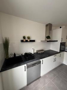 a kitchen with white cabinets and a black counter top at Centre ville - Le Creusot in Le Creusot