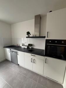 a kitchen with white cabinets and black counter tops at Centre ville - Le Creusot in Le Creusot