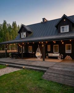 a black house with a porch and a patio at Mazurska Chata Rydzewo in Rydzewo