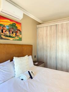 a bedroom with a white bed with a painting on the wall at Dunamis Lodge in Giyani