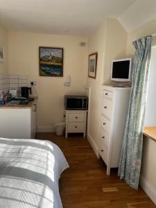 a bedroom with a bed and a desk with a tv at Otter's Reach in Budleigh Salterton