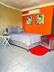 a bedroom with an orange wall and a bed and a chair at Mbizana Lifestyle in Monzi