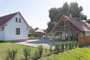 a white house with a wooden roof and a yard at Hárs Vendégház in Balatonendréd