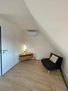 a living room with a black chair and a piano at - Le 4ème Tourbillon- in Molsheim +2 photos