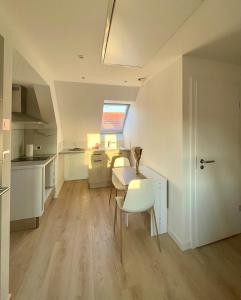 a kitchen with white cabinets and a table and chairs at - Le 4ème Tourbillon- in Molsheim