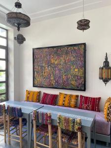a table with colorful pillows and a painting on the wall at Riad Maison de ville piscine privée in El Jadida