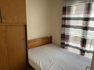 a small bedroom with a bed and a curtain at petite apartment in Asprovalta