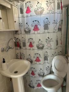 a bathroom with a sink and a toilet and a shower curtain at petite apartment in Asprovalta +5 photos