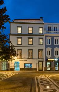 a large white building with windows at night at Matriz 55 in Ponta Delgada