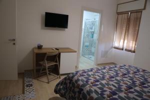 a bedroom with a bed and a desk and a television at B&B Le Eolie in Milazzo