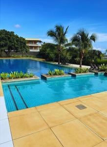 a large swimming pool with blue water and palm trees at Port Chambly Waterside Villa in Terre Rouge +2 photos