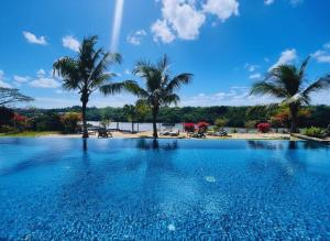 a large swimming pool with palm trees on the beach at Port Chambly Waterside Villa in Terre Rouge