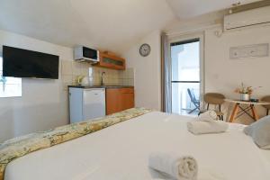 a bedroom with two white beds and a kitchen at Apartments Villa Arta in Murter