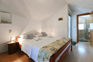 a white bedroom with a large bed and a window at Apartments Villa Arta in Murter