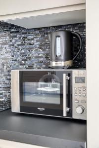 a microwave with a pot on top of it at Elegant apartment with pool and parking in Losone