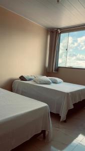 two beds in a room with a window at Suíte Luxo Casal Duplo in Areia