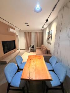 a living room with a wooden table and blue chairs at Casa Del Sol 2 - Shengjin in Shëngjin