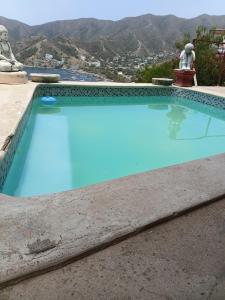 a blue swimming pool with mountains in the background at Buena Vista in Taganga