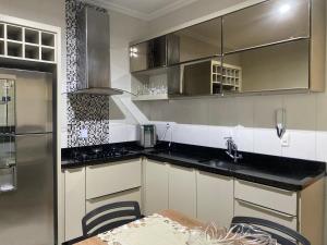 a kitchen with white cabinets and a table and a sink at Casa Betel in Anápolis