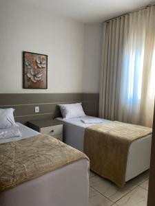 a hotel room with two beds and a window at Casa Betel in Anápolis