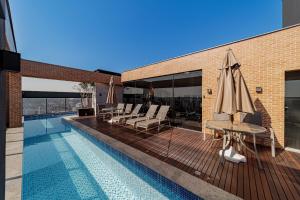 a swimming pool with a table and an umbrella at Flipchave | Highline design in Joinville