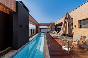 a swimming pool with a table and an umbrella at Flipchave | Highline design in Joinville