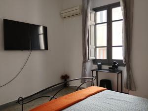 a bedroom with a bed and a television on the wall at CASTEDDU rooms in Cagliari