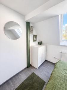 a white bedroom with a bed and a mirror at Family & Work Apartment in Schopfloch