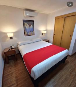 a hotel room with a large bed with a red blanket at Hotel Jardin in San Cristóbal