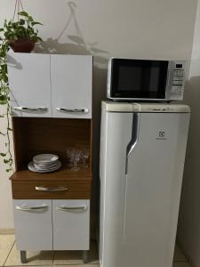 a microwave on top of a refrigerator next to a cabinet at Ap Perfeito! Condomínio fechado e garagem coberta in Tangara da Serra