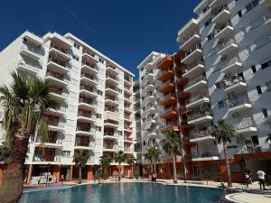 an apartment complex with a swimming pool and palm trees at Casa Del Sol Studio - Shengjin in Shëngjin