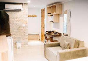 a living room with a couch and a kitchen at Canto da Canoa Suítes I in Arraial do Cabo