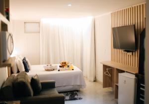 a hotel room with a bed and a television at Canto da Canoa Suítes I in Arraial do Cabo