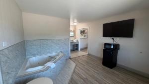 a bathroom with a tub and a flat screen tv at Harmony Inn and Suites in Beaumont