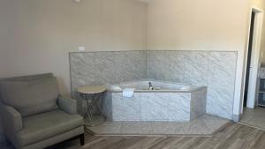 a bathroom with a bath tub and a chair at Harmony Inn and Suites in Beaumont