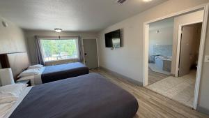a hotel room with two beds and a bathroom at Harmony Inn and Suites in Beaumont