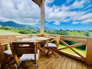 a wooden deck with a table and chairs on a balcony at Casa Ido sat Pestera Moieciu in Peştera