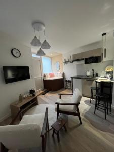 a living room with a couch and a table and a kitchen at Place aux fleurs - Le cocon in Dole