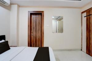 a bedroom with a bed and a wooden door at Hotel O Hotel Krishna's Residency in Indore