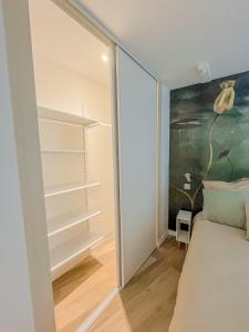 a bedroom with a closet with a bed and a painting at Place aux fleurs - Le cocon in Dole