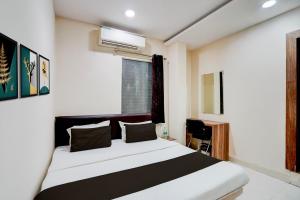 a bedroom with a white and black bed and a window at Hotel O Hotel Krishna's Residency in Indore +21 photos