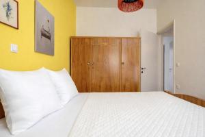 a bedroom with a white bed and a wooden cabinet at Dafni Local Style, 1 Min from Main Beach in Kardamaina